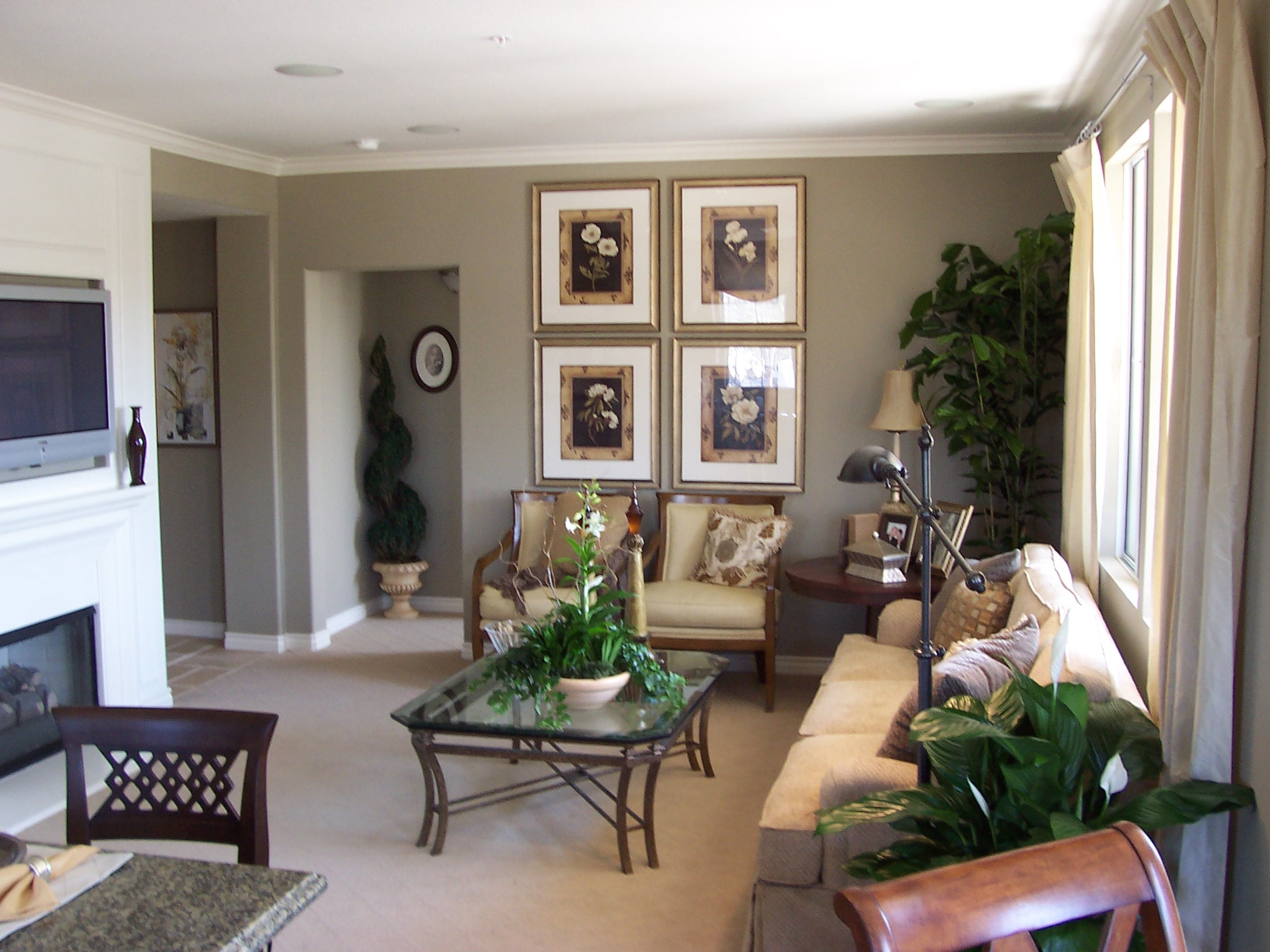 Living room with botanical artwork, tailored seating, and greenery