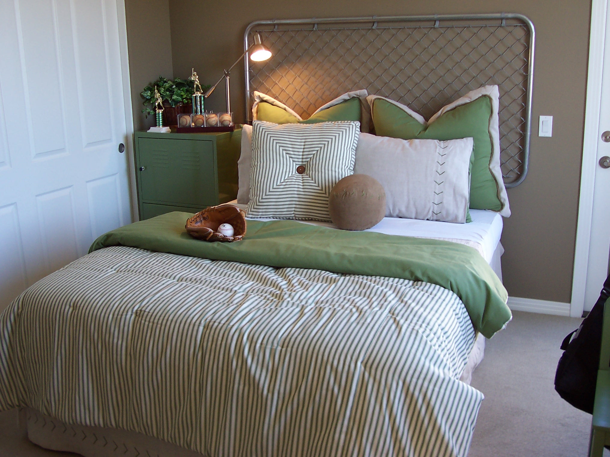 Bedroom with green bedding and a woven metal headboard