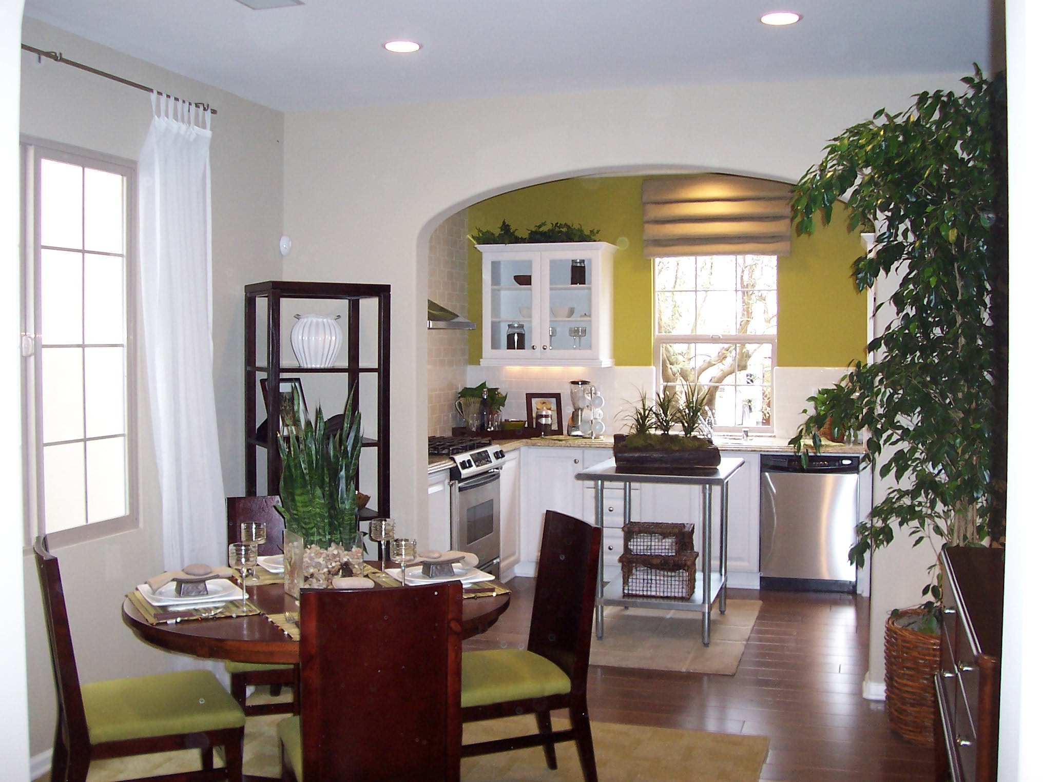 Kitchen and dining area with white cabinetry, green accents, and dark wood furniture