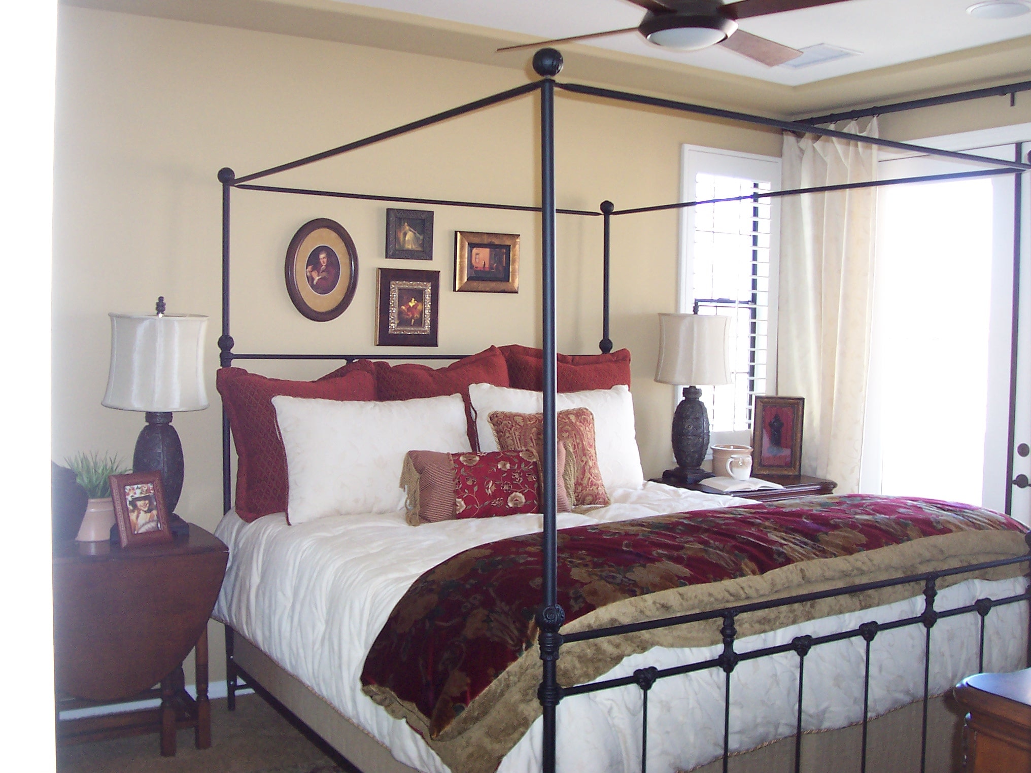 Bedroom with iron canopy bed and layered burgundy bedding