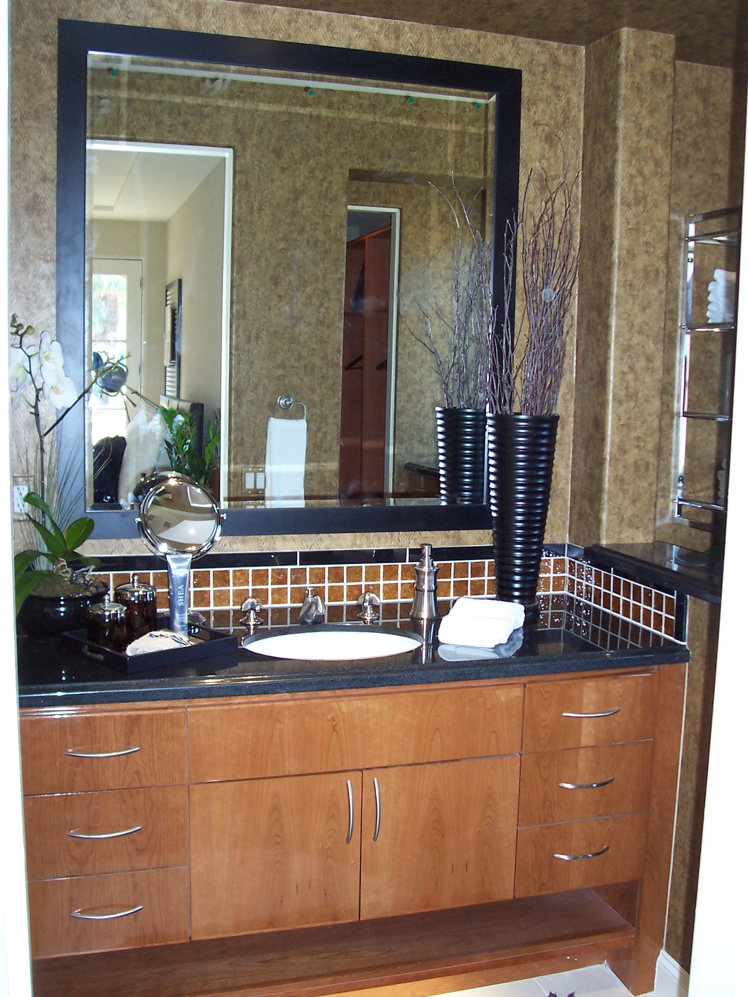 Primary bathroom vanity with dark countertop and wood cabinetry